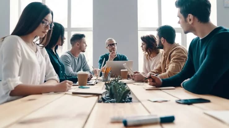 A cross-functional team reviewing documentation together around a meeting table